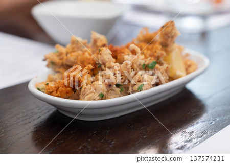 Crispy fried squid tentacles served on a plate with a lemon wedge in a restaurant setting, a golden seafood appetizer with crunchy texture and savory flavor. 137574231