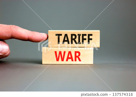Trade tariff war symbol. Concept word Tariff war on beautiful wooden blocks. Beautiful grey paper background. Businessman's hand. Business trade tariff wars concept. Copy space. 137574318