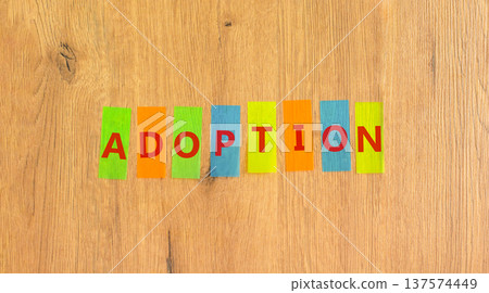 Adoption word symbol. Concept word Adoption on beautiful colored papers. Beautiful wooden background. Business psychological support help adoption word concept. Copy space. 137574449