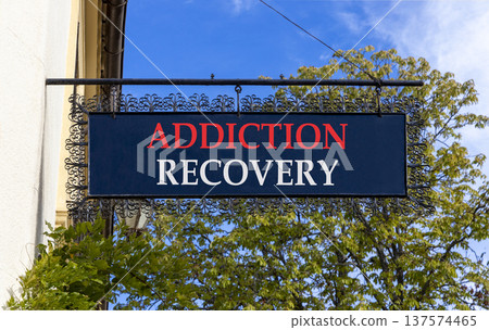 Addiction recovery symbol. Concept words Addiction recovery on beautiful big black road sign. Beautiful blue sky green trees background. Psychology addiction recovery concept. Copy space. Addiction recovery symbol. Concept words Addiction recovery on beautiful big black road sign. Beautiful blue sky green trees background. Psychology addiction recovery concept. Copy space. 137574465