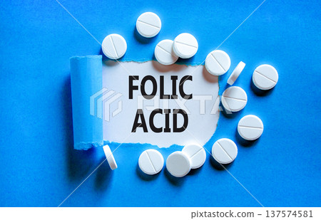 Folic acid symbol. Concept words Folic acid on beautiful white paper. White pills tablets. Beautiful blue background. Medical healthy lifestyle folic acid concept. Folic acid symbol. Concept words Folic acid on beautiful white paper. White pills tablets. Beautiful blue background. Medical healthy lifestyle folic acid concept. 137574581