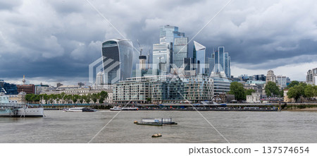 Modern glass skyscrapers in the London financial district rise across the River Thames representing contemporary urban architecture and a dynamic business city skyline. 137574654