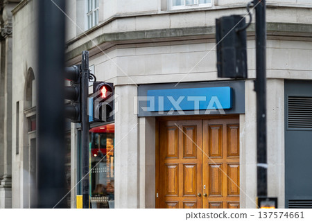 Blue sign box above Wooden door and stone building facade beside a red traffic signal in a London street environment. Blue sign box above Wooden door and stone building facade beside a red traffic signal in a London street environment. 137574661