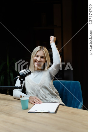 Excited female radio host celebrating success during a podcast recording Excited female radio host celebrating success during a podcast recording 137574799
