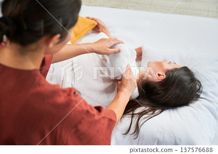Masseuse making thai yoga massage. Woman therapist doing traditional massage treatment for female patient. Client lying on mat, meditating, enjoying hand massage in calm atmosphere. Cropped view. 137576688