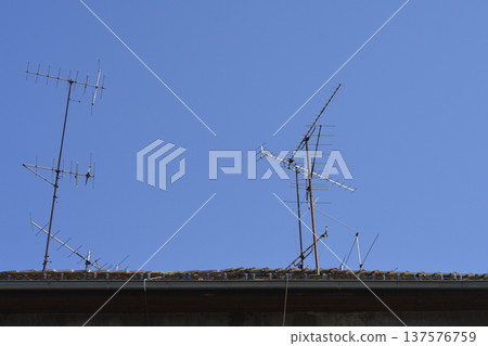 Television antennas on a house roof against blue sky 137576759