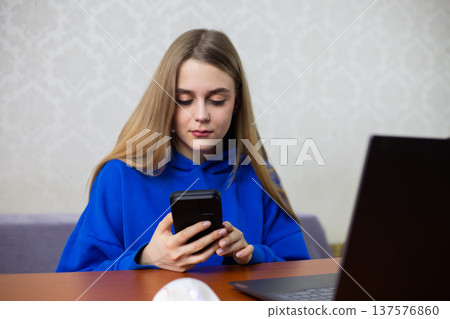 Young woman smiles happily while checking loan approval on smartphone. She receives good news from online bank, credit application accepted. Positive financial moment at home Young woman smiles happily while checking loan approval on smartphone. She receives good news from online bank, credit application accepted. Positive financial moment at home 137576860
