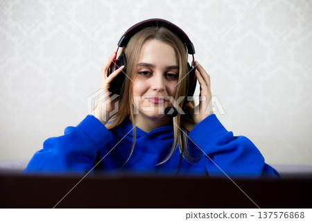Young woman smiles serenely while listening to therapy session or affirmations on headset, practices self-care and mental wellness through audio guidance at home. Healing and mindfulness concept 137576868