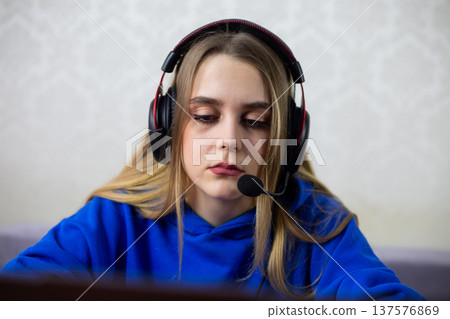 Exhausted young woman sits with poor posture at laptop, wearing headphones. She looks sad and unmotivated during long remote work or study session. Burnout and mental fatigue concept at home Exhausted young woman sits with poor posture at laptop, wearing headphones. She looks sad and unmotivated during long remote work or study session. Burnout and mental fatigue concept at home 137576869