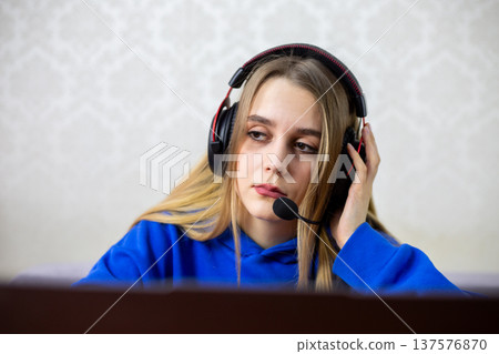 Young female podcaster listens intently to guest during live interview, wears headphones, gaze directed away from laptop screen. Engaging conversation and content creation concept at home studio Young female podcaster listens intently to guest during live interview, wears headphones, gaze directed away from laptop screen. Engaging conversation and content creation concept at home studio 137576870