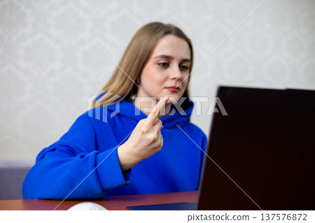 Happy young woman points index finger at laptop screen celebrating first place ranking. She learns her favorite project or company achieved top spot. Success and victory concept at home Happy young woman points index finger at laptop screen celebrating first place ranking. She learns her favorite project or company achieved top spot. Success and victory concept at home 137576872