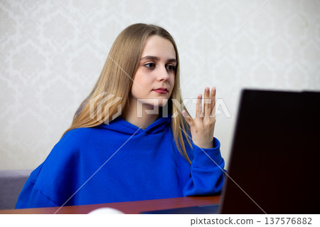 Excited blonde fan raises four fingers celebrating fourth goal and dominant score. Her team crushes opponent in football match, she cheers wildly. Intense victory reaction at home 137576882