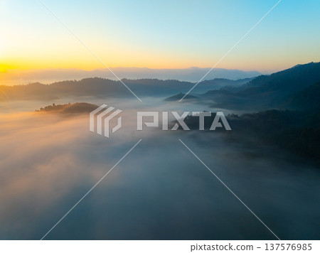 Aerial view of flowing fog waves on mountain tropical rainforest,Bird eye view image over the clouds Amazing nature background with clouds and mountain peaks in Thailand 137576985