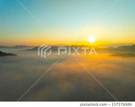 Aerial view of flowing fog waves on mountain tropical rainforest,Bird eye view image over the clouds Amazing nature background with clouds and mountain peaks in Thailand 137576986