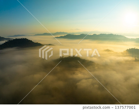 Aerial view of flowing fog waves on mountain tropical rainforest,Bird eye view image over the clouds Amazing nature background with clouds and mountain peaks in Thailand Aerial view of flowing fog waves on mountain tropical rainforest,Bird eye view image over the clouds Amazing nature background with clouds and mountain peaks in Thailand 137577001