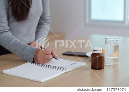 Morning routine: Writing in a notebook with medication and water 137577074