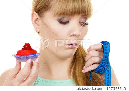 Woman holds cupcake trying to resist temptation Woman holds cupcake trying to resist temptation 137577243