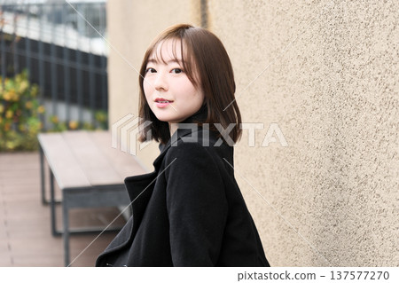 A female model looking back on a winter street corner. A natural and clear outdoor portrait with a soft wall as the background. A female model looking back on a winter street corner. A natural and clear outdoor portrait with a soft wall as the background. 137577270