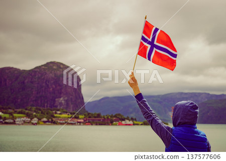 Tourist with norwegian flag on fjord Tourist with norwegian flag on fjord 137577606