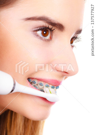 Woman smiling cleaning teeth with braces 137577927