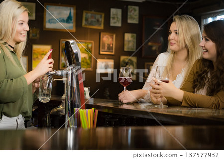 Young woman dispensing beer in bar from spigot Young woman dispensing beer in bar from spigot 137577932