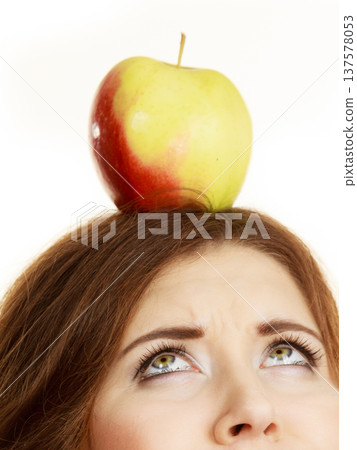 Woman holds on head apple fruit looking up Woman holds on head apple fruit looking up 137578053