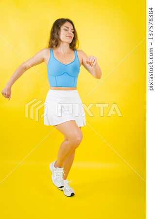 Woman dancing wearing sportswear on yellow background Woman dancing wearing sportswear on yellow background 137578384