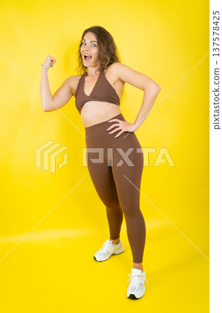 Confident woman flexing bicep showing strength and fitness Confident woman flexing bicep showing strength and fitness 137578425