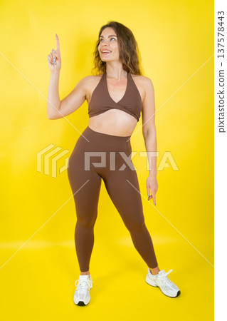 Young woman smiling pointing up showing advertising copy space 137578443