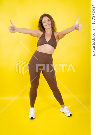 Smiling woman giving two thumbs up for fitness Smiling woman giving two thumbs up for fitness 137578454