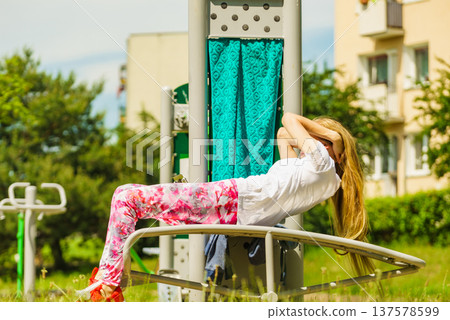 Girl doing situps in outdoor gym Girl doing situps in outdoor gym 137578599