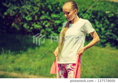 Girl doing exercises outdoor, using resistance fit band. Girl doing exercises outdoor, using resistance fit band. 137578600