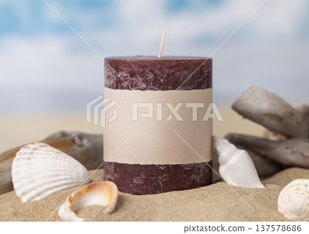 Pillar candle mockup with blank label on beige sand with seashells and driftwood close up 137578686
