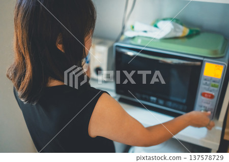 Woman using a microwave 137578729