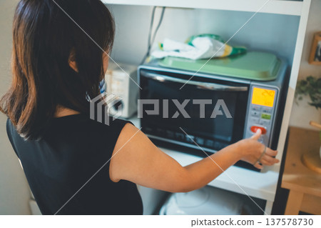 Woman using a microwave 137578730