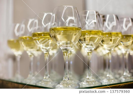 Many glasses filling a table with white wine for a party or event Many glasses filling a table with white wine for a party or event 137579360