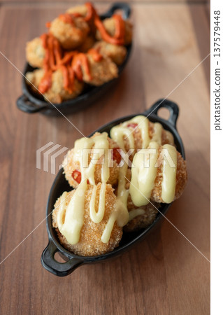Crispy bites with creamy sauce and vibrant drizzle on a wooden table Crispy bites with creamy sauce and vibrant drizzle on a wooden table 137579448