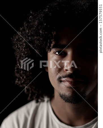 Young african-american man with curly hair posing in the shadows 137579551