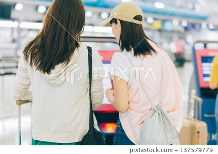 Two women checking in by themselves at the airport. (Photography courtesy of Kansai International Airport (KIX)) 137579779