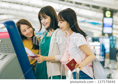 Three women checking in by themselves at the airport. (Photography courtesy of Kansai International Airport (KIX)) Three women checking in by themselves at the airport. (Photography courtesy of Kansai International Airport (KIX)) 137579848