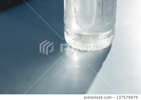 一瓶清爽冰涼的礦泉水塑膠瓶底，水滴清晰可見，光線透過瓶身照射進來。 137579879