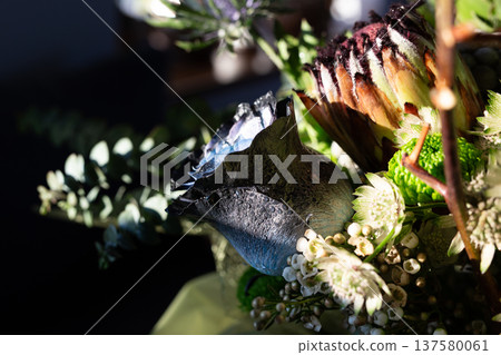 Title: Artistic floral bouquet with blue rose and protea on dark background 137580061