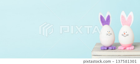 Decorative Easter eggs with bunny ears on wooden surface, pastel background Decorative Easter eggs with bunny ears on wooden surface, pastel background 137581301