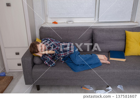 Child resting on a couch in a cozy indoor setting during the afternoon 137581607
