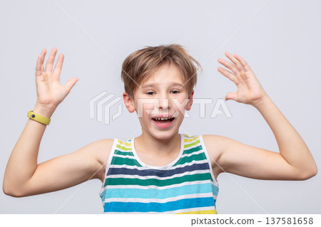 Excited boy expressing joy with hands raised in a cheerful setting during daytime Excited boy expressing joy with hands raised in a cheerful setting during daytime 137581658
