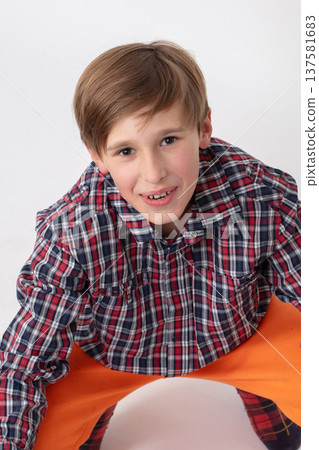 A teenage boy in a checkered shirt looks at the camera and smiles. A teenage boy in a checkered shirt looks at the camera and smiles. 137581683