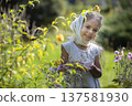 Young girl in a garden enjoying colorful flowers on a sunny day 137581930
