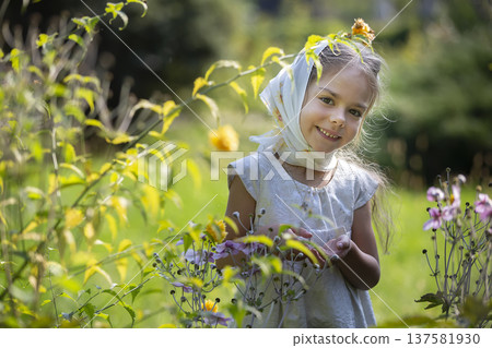 Young girl in a garden enjoying colorful flowers on a sunny day 137581930