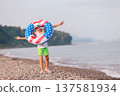 Child enjoying playing on beach with inflatable ring in american flag colors on sunny day 137581934