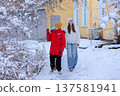 A boy and a girl in winter clothes are walking in front of a house. 137581941